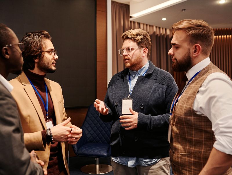 Four men with lanyards deep in conversation at a business event