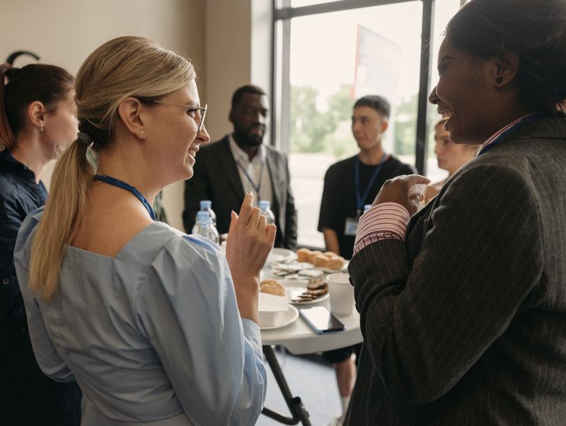Two women laughing together over coffee at an event